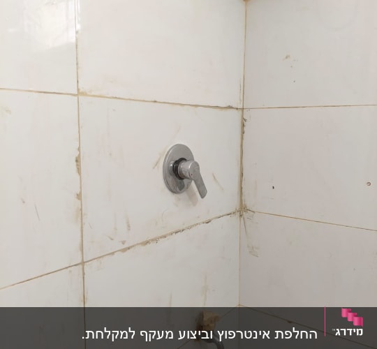 ברזים ומקלחת על קיר אריחים לבנים